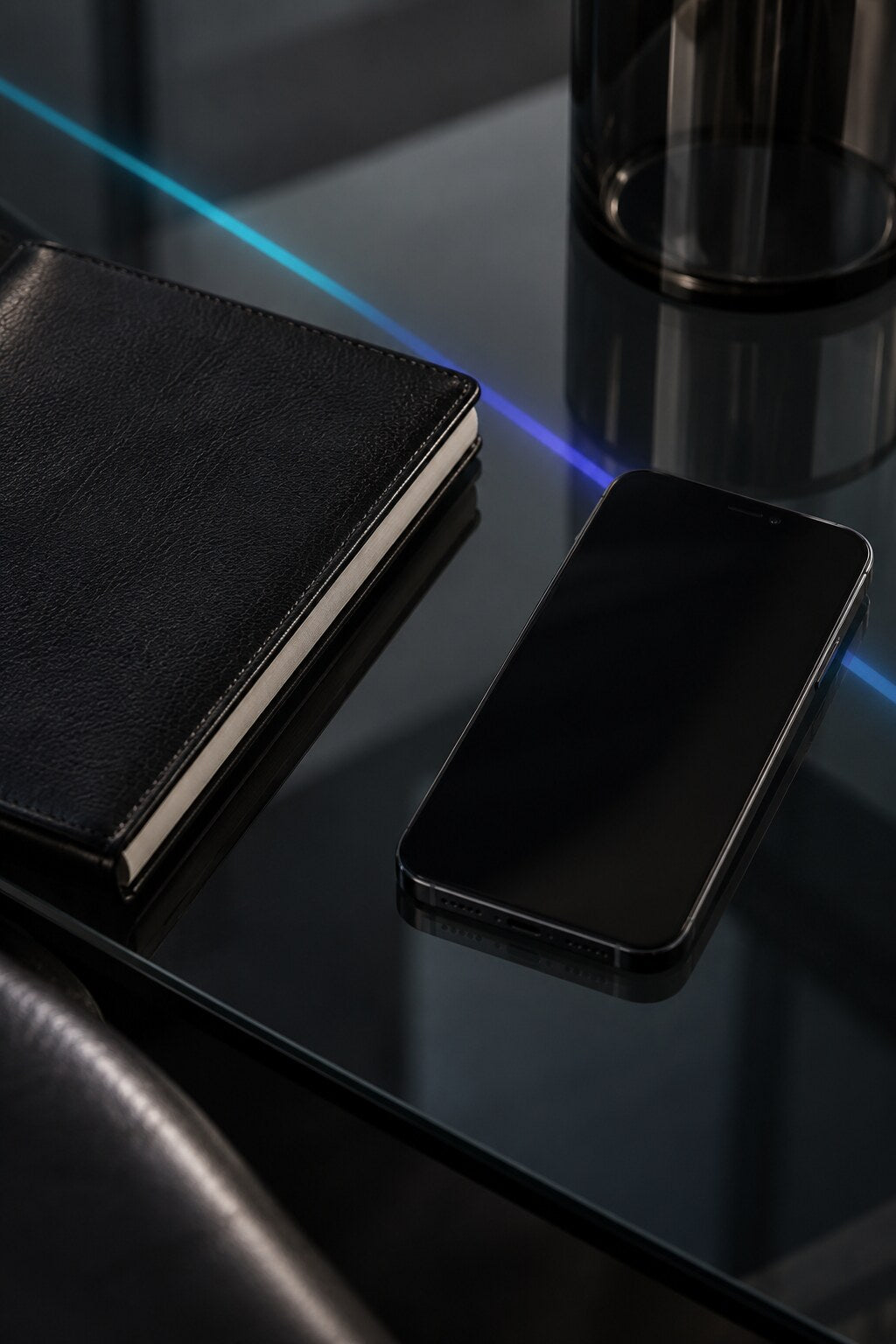 Leather notebook and phone under a narrow cyan light