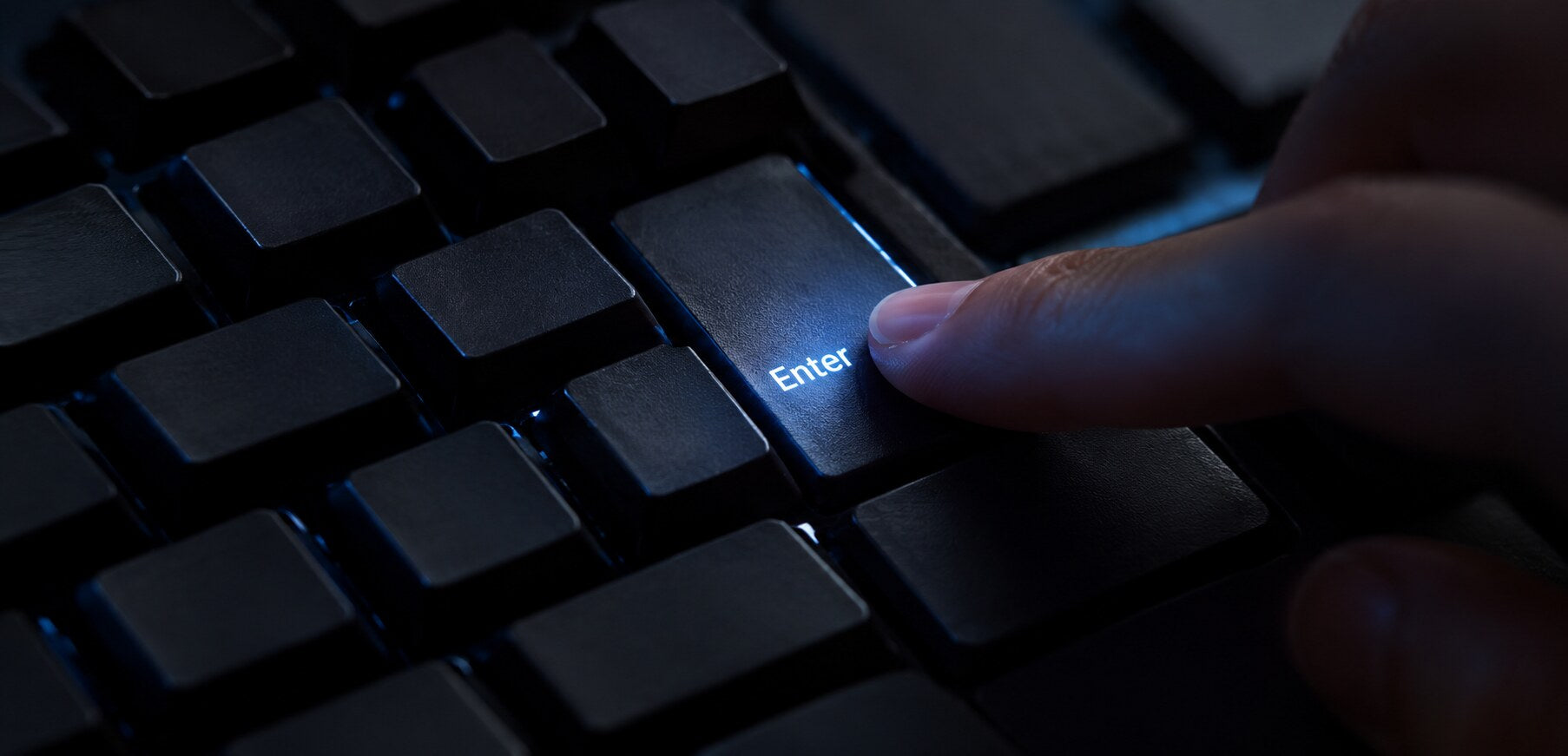 Hand pressing an illuminated Enter key